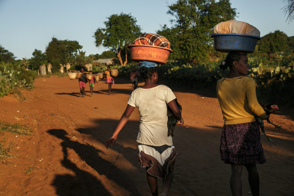 Young women return home after washing clothes near a water source located several kilometers from their home.
